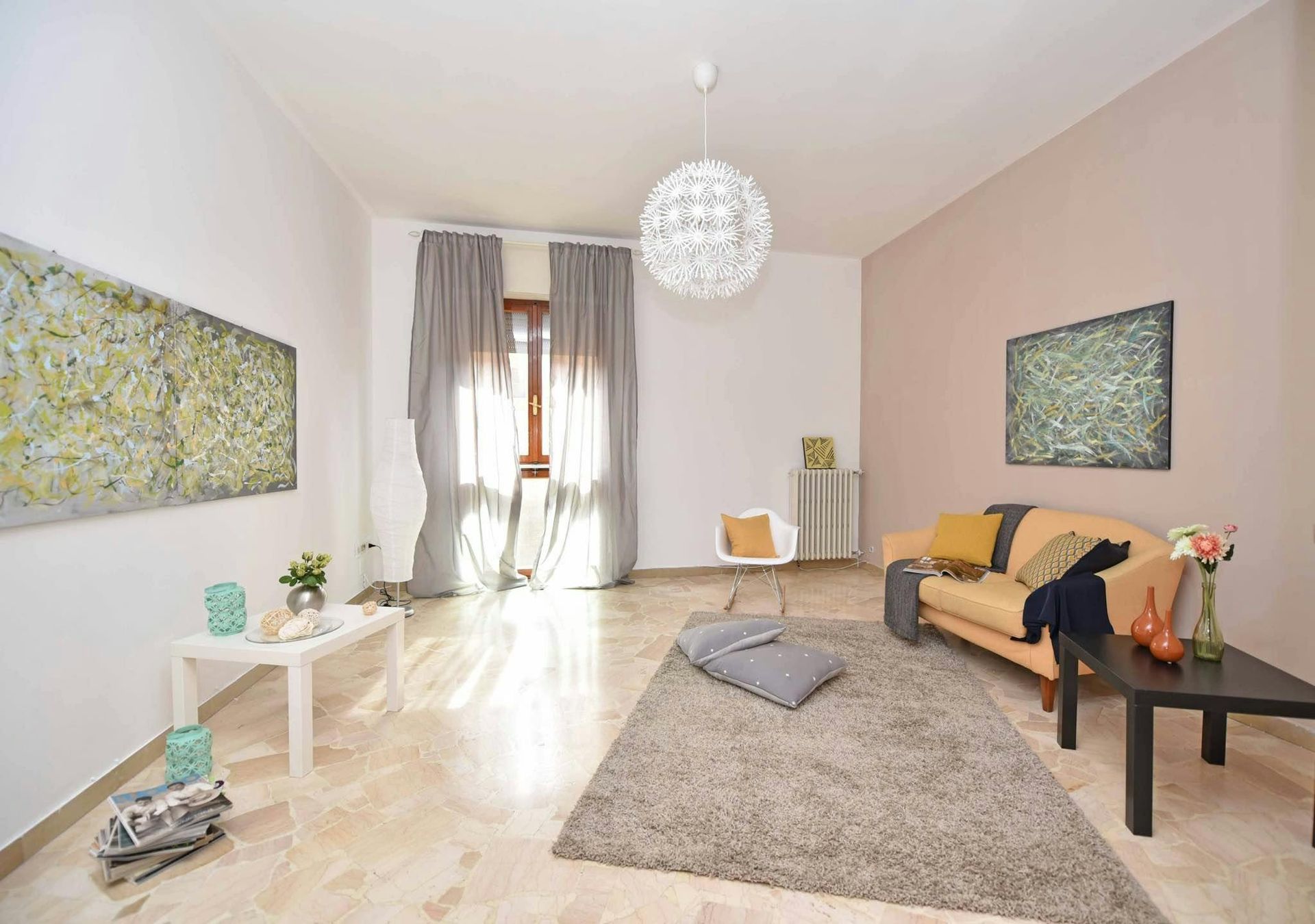 Living room with beige sofa, artwork, curtains, and a fluffy rug on a marble floor.