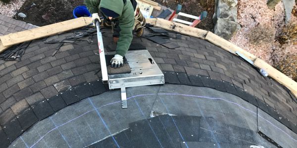 A man is working on a roof with a ladder in the background.