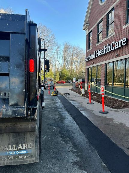 A dump truck parked beside a brick building marked 