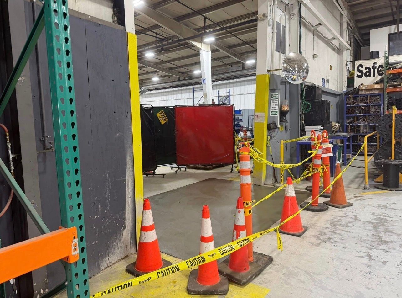 Workers pave a driveway with asphalt using heavy machinery and a plate compactor at a construction site.