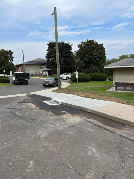 A red excavator works on a muddy, snow-covered site near a distant playground.