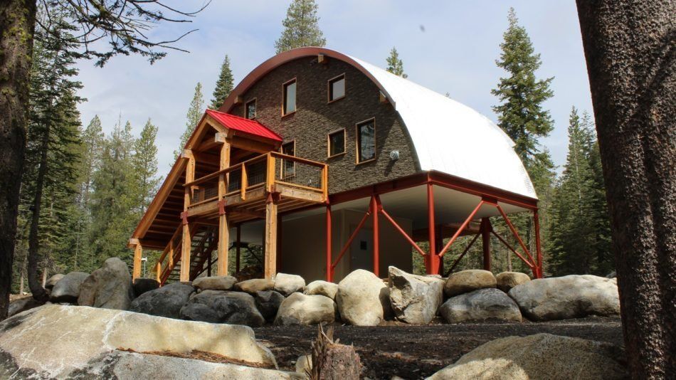 A house with a red roof is surrounded by trees and rocks