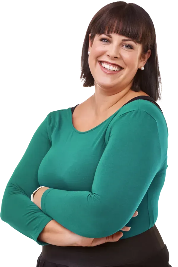 Woman with dark hair, arms crossed, wearing a green long-sleeved shirt, smiling.