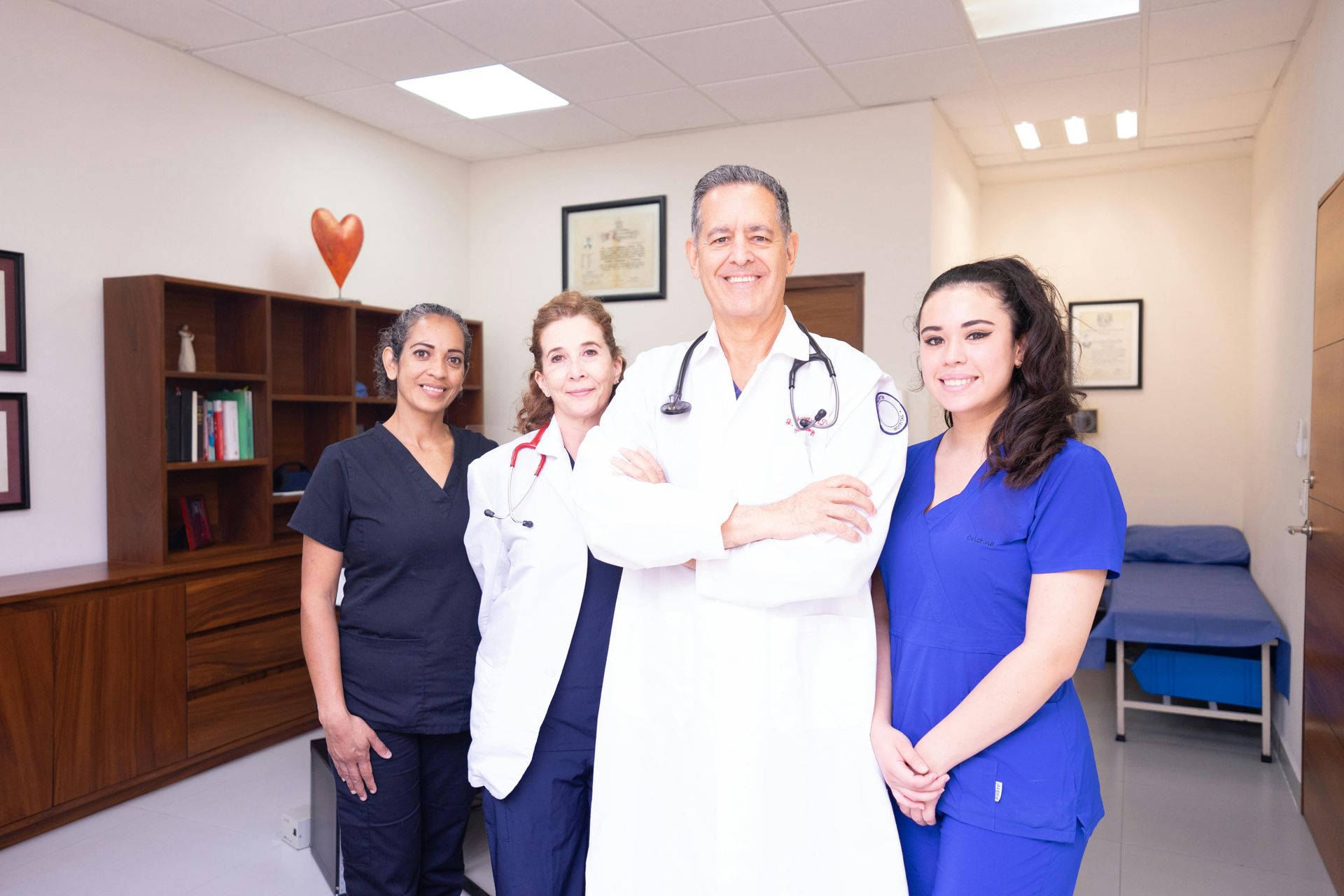 Medical staff in an office setting. Doctor with stethoscope and three assistants smiling.
