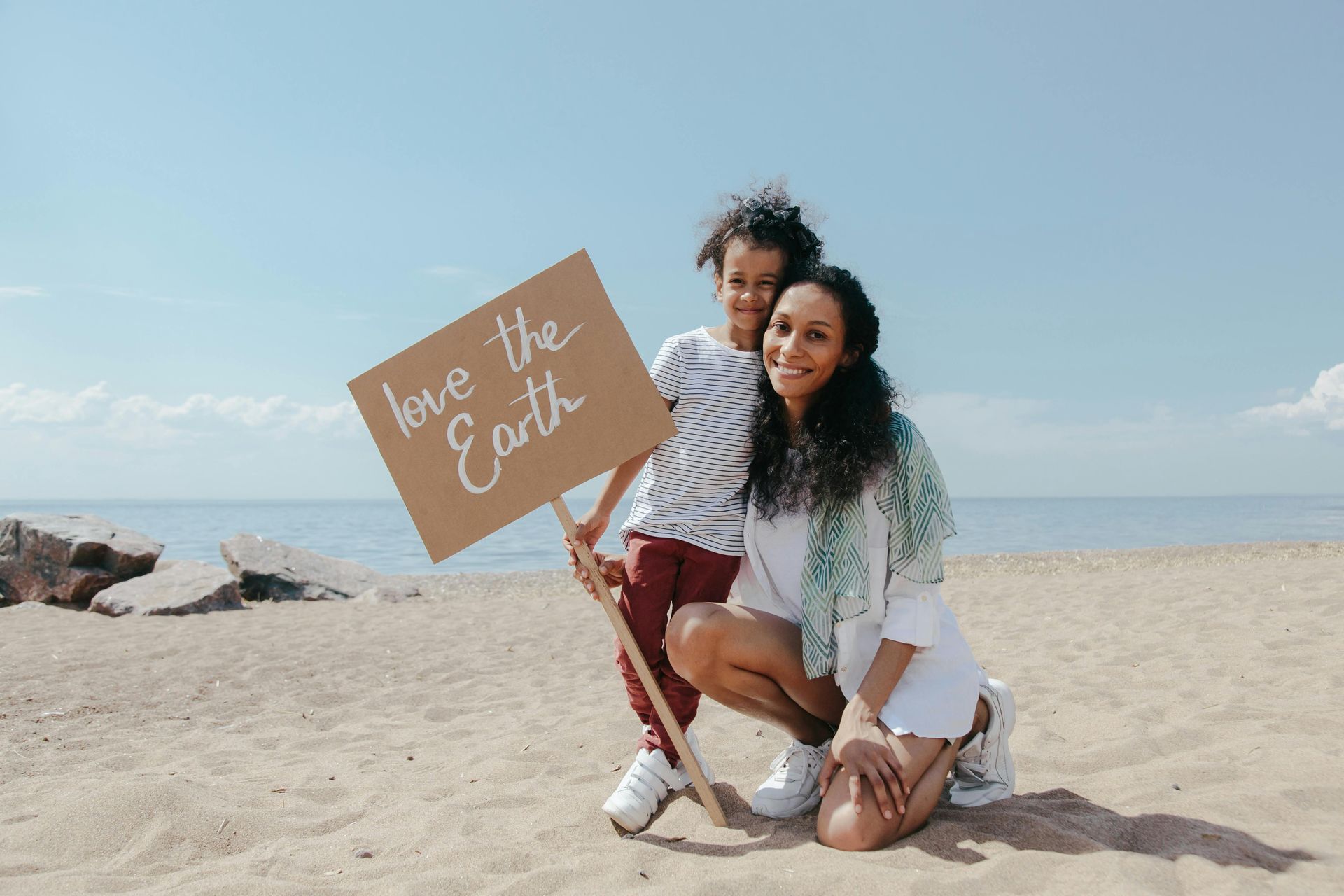 A mother and child on a beach holding a sign that says 