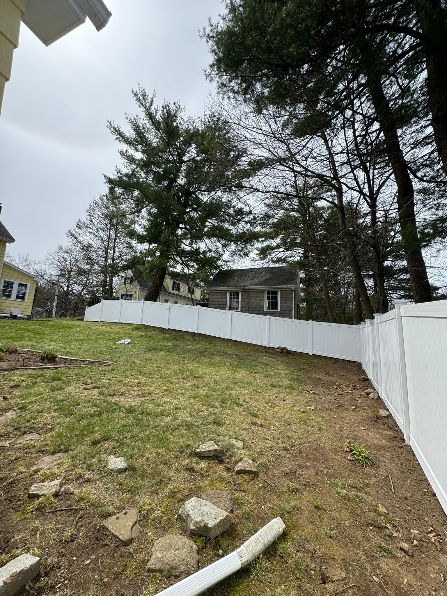 A white fence surrounds a grassy yard with trees in the background.