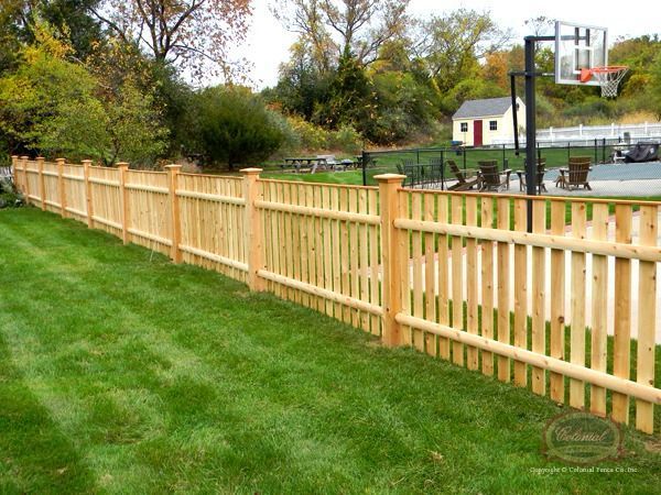 A wooden fence with a basketball hoop in the background