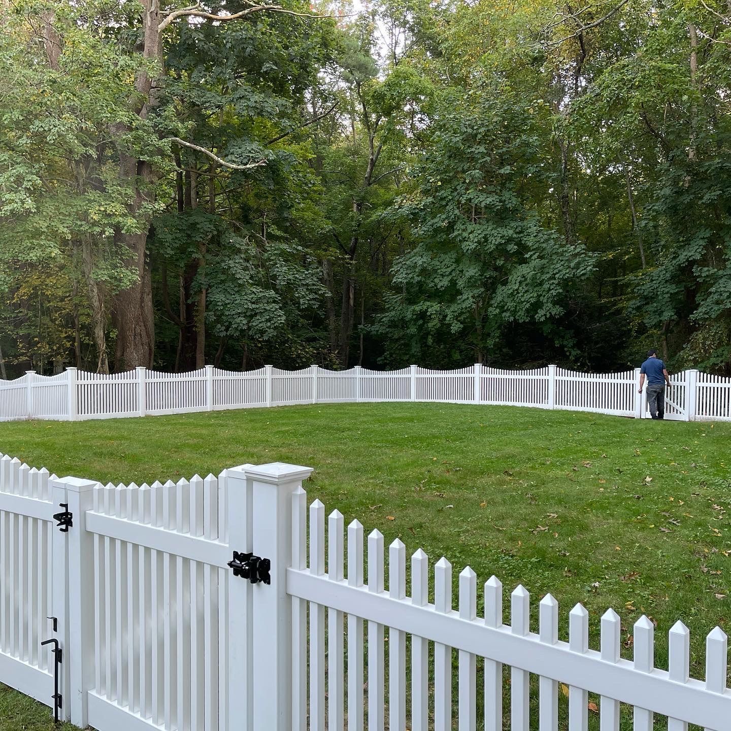 A white picket fence surrounds a lush green field.