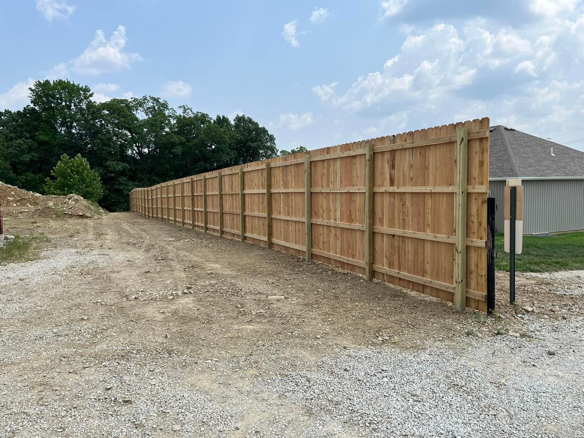 A long wooden fence is sitting on the side of a dirt road.