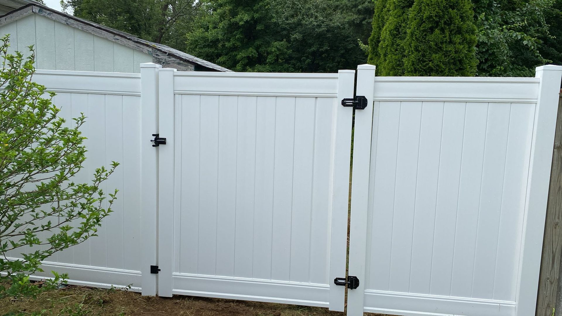 A white vinyl fence with a gate attached to it.
