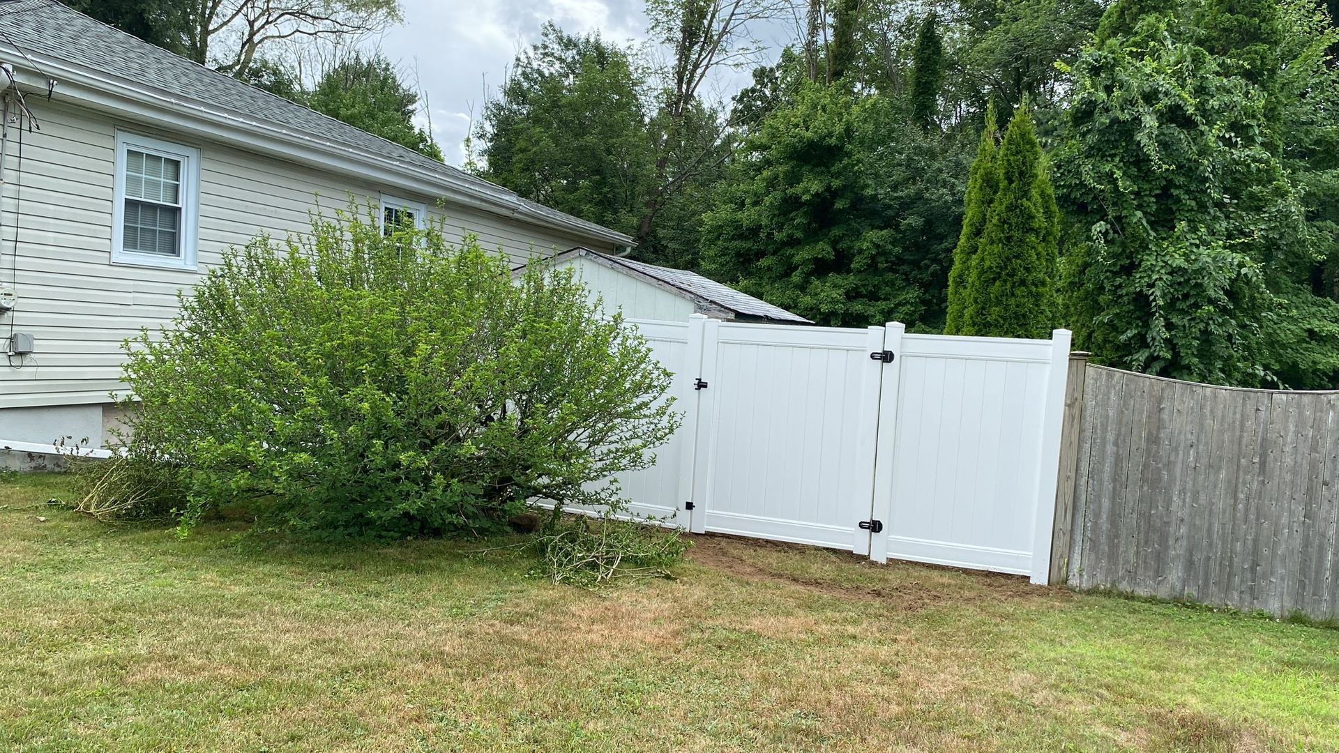 There is a white fence in the backyard of a house.