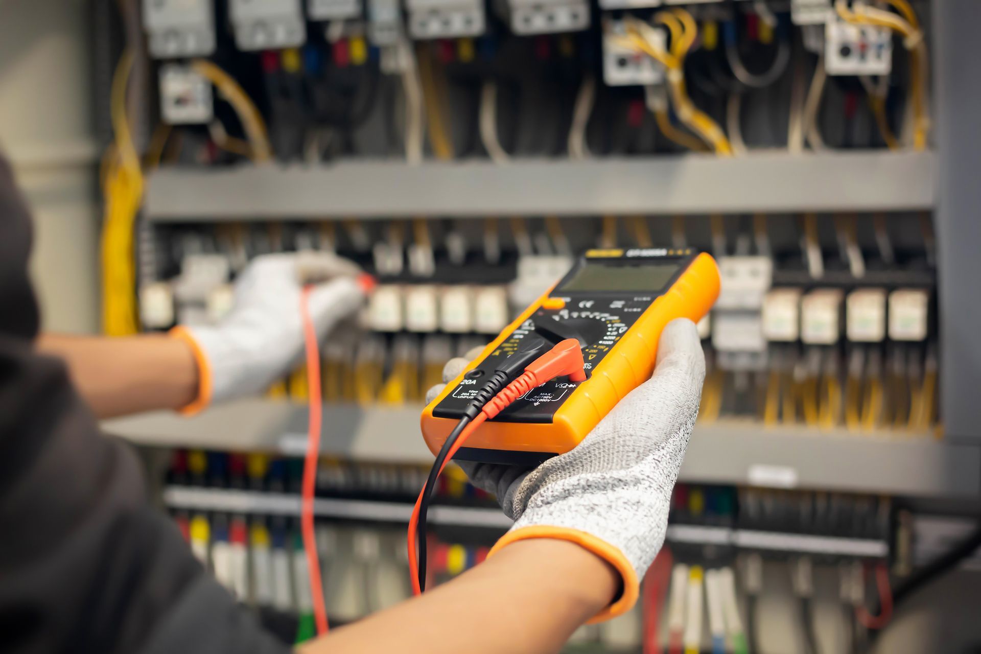 Hogue Electric technician with a multimeter checking an electrical panel.