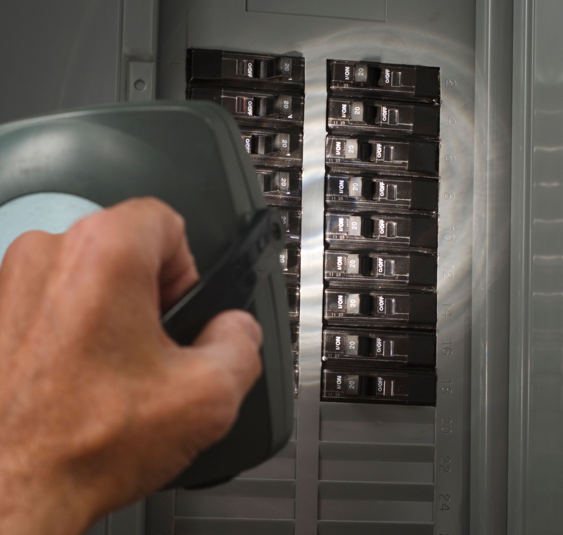A person is holding a flashlight in front of a electrical panel.