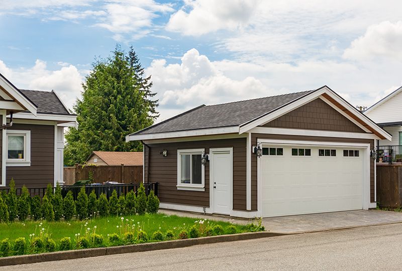 a brown house with a white garage next to it .