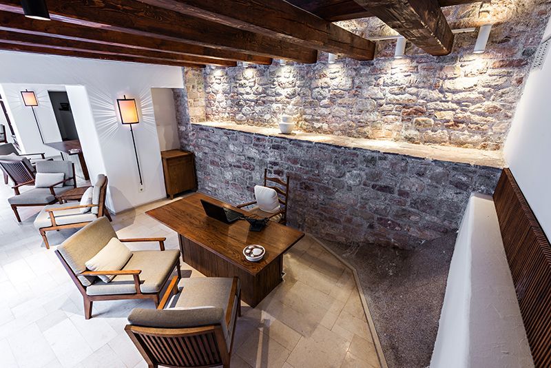 a living room with a wooden table and chairs and a stone wall .