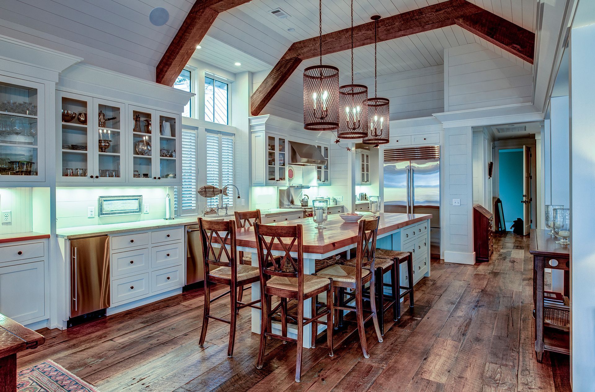 a large kitchen with white cabinets and wooden floors