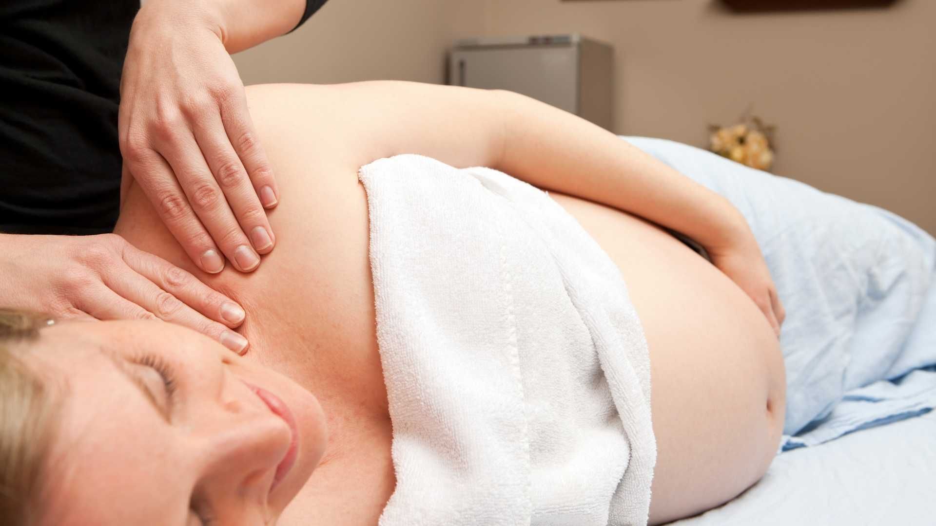 A pregnant woman is getting a massage at a spa