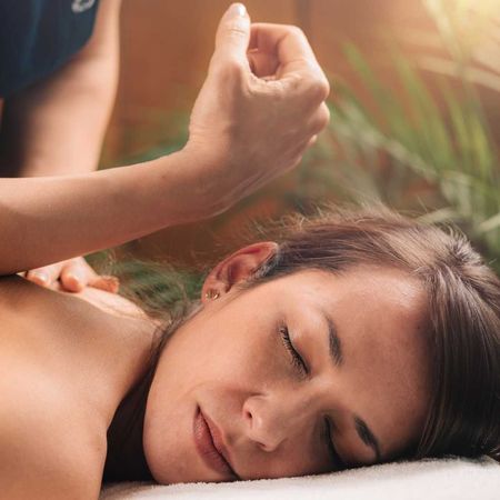 A woman is laying on a bed getting a massage.