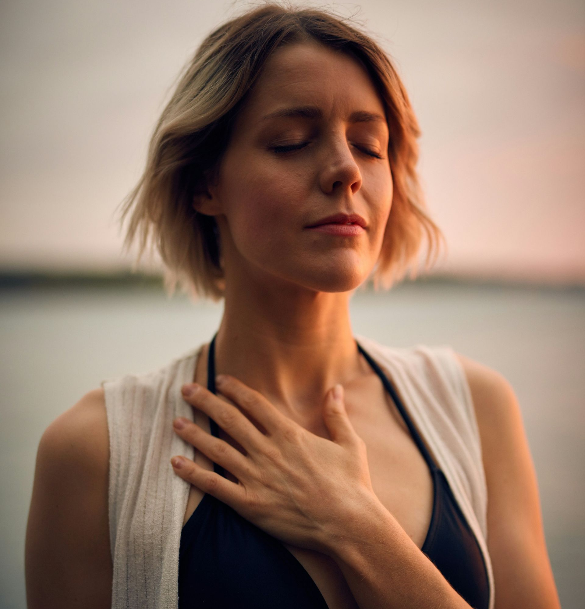 Bathtub filled with blue water, towels, bath bomb, and a lit candle.