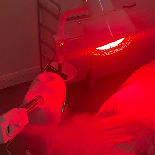 A red light is shining on a person 's face.