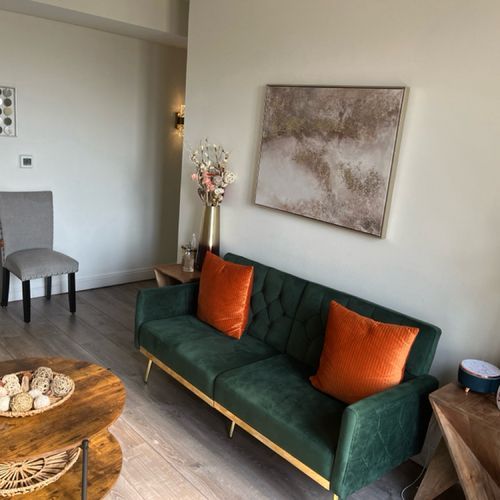 A living room with a green couch and orange pillows