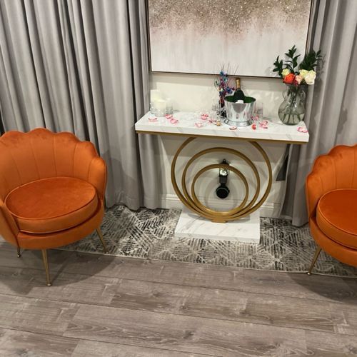 Two orange chairs are sitting next to a table in a living room.