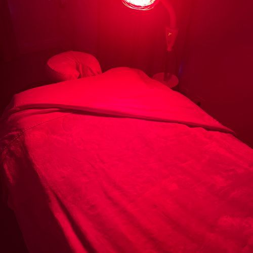 A person is laying on a massage table under a red light.