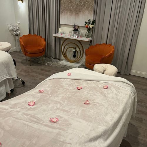 A massage table with rose petals on it in a room with chairs.