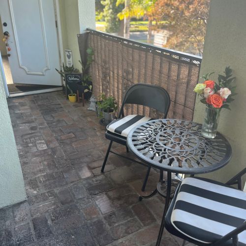 A balcony with a table and chairs and a vase of flowers