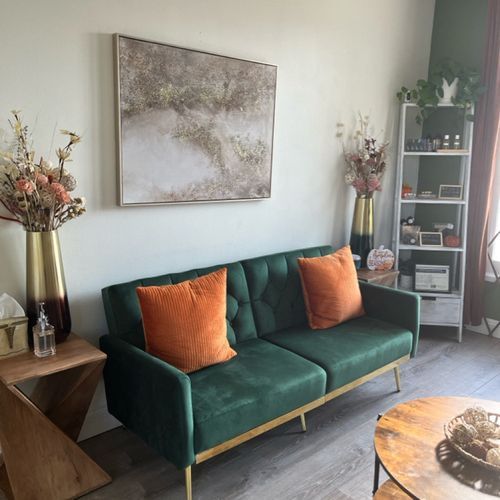 A living room with a green couch and orange pillows.