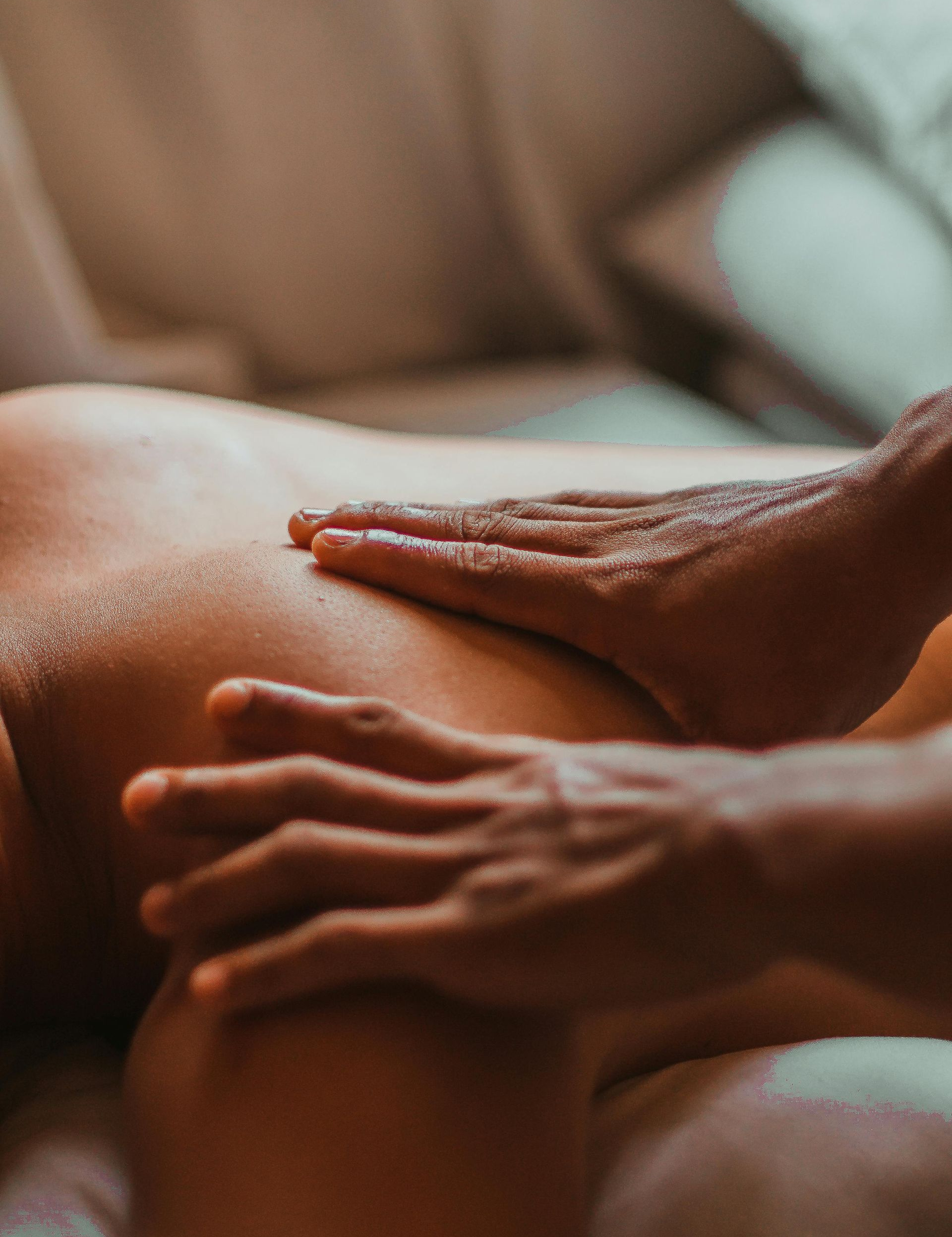 Hands massaging someone's back; focus on the skin and the massage.