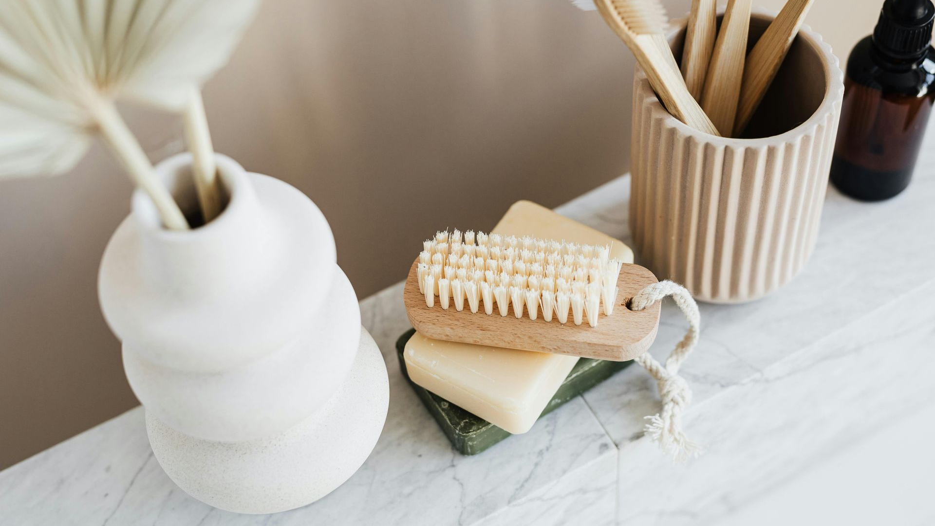 Bathroom items: vase, soap, bamboo toothbrushes, a brush, and oil bottle.