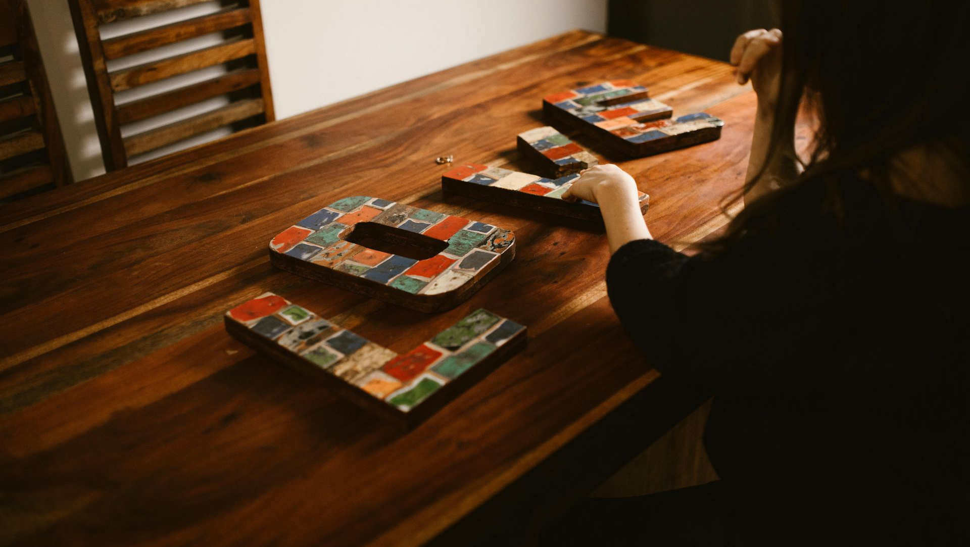 Person arranging mosaic tile letters that spell