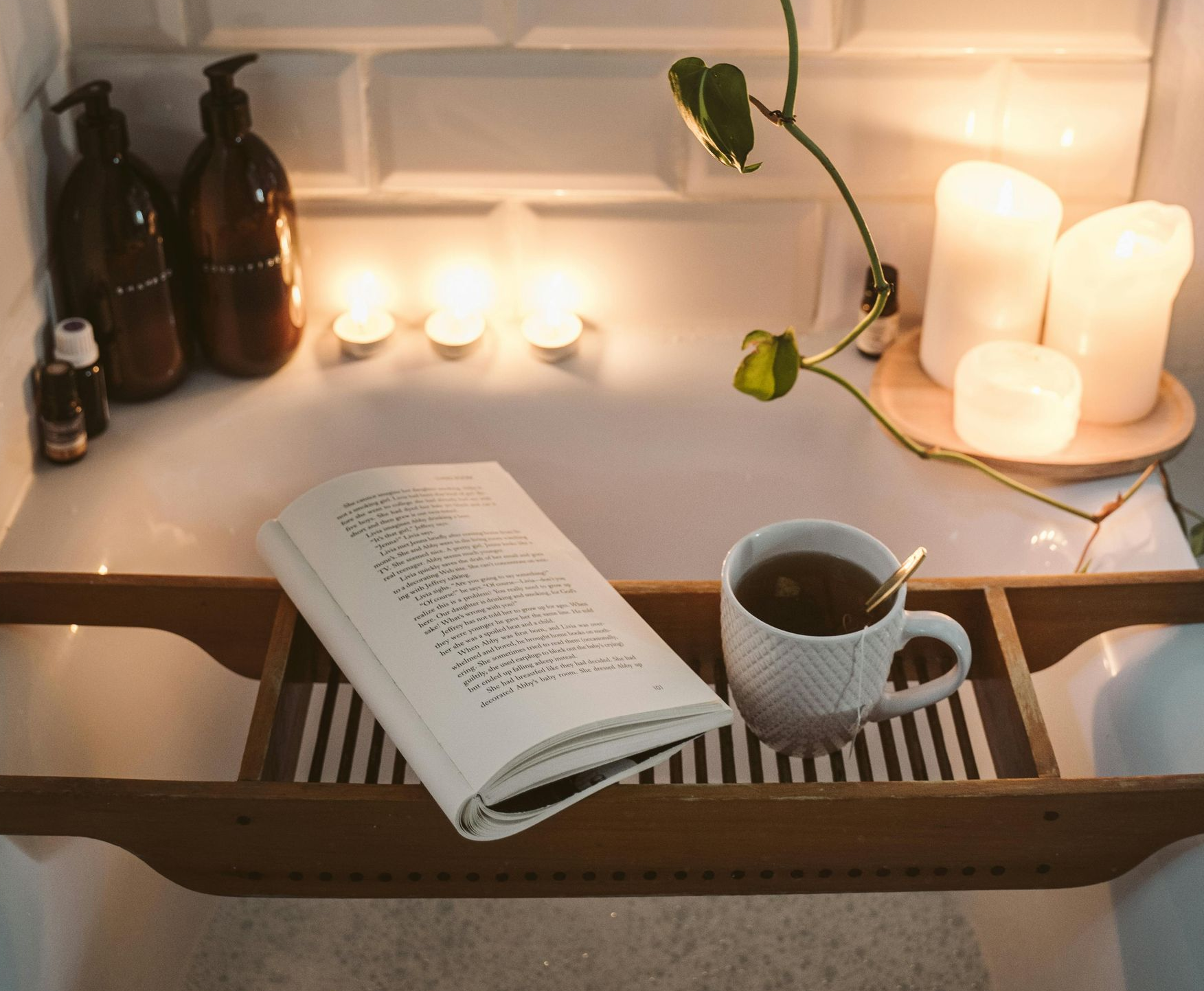 Bathtub tray with book, tea, candles, and toiletries.