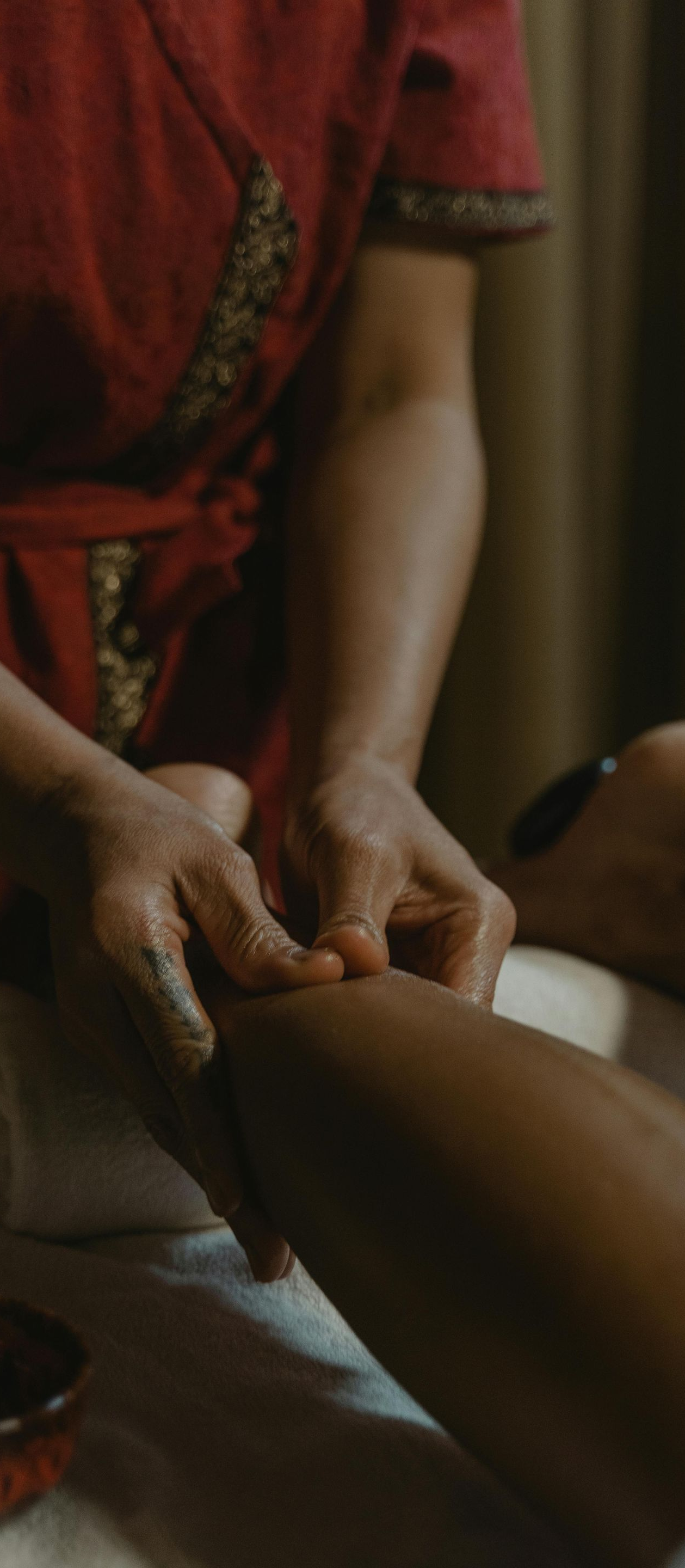 Person massaging another person's leg in a dimly lit setting, possibly a spa.