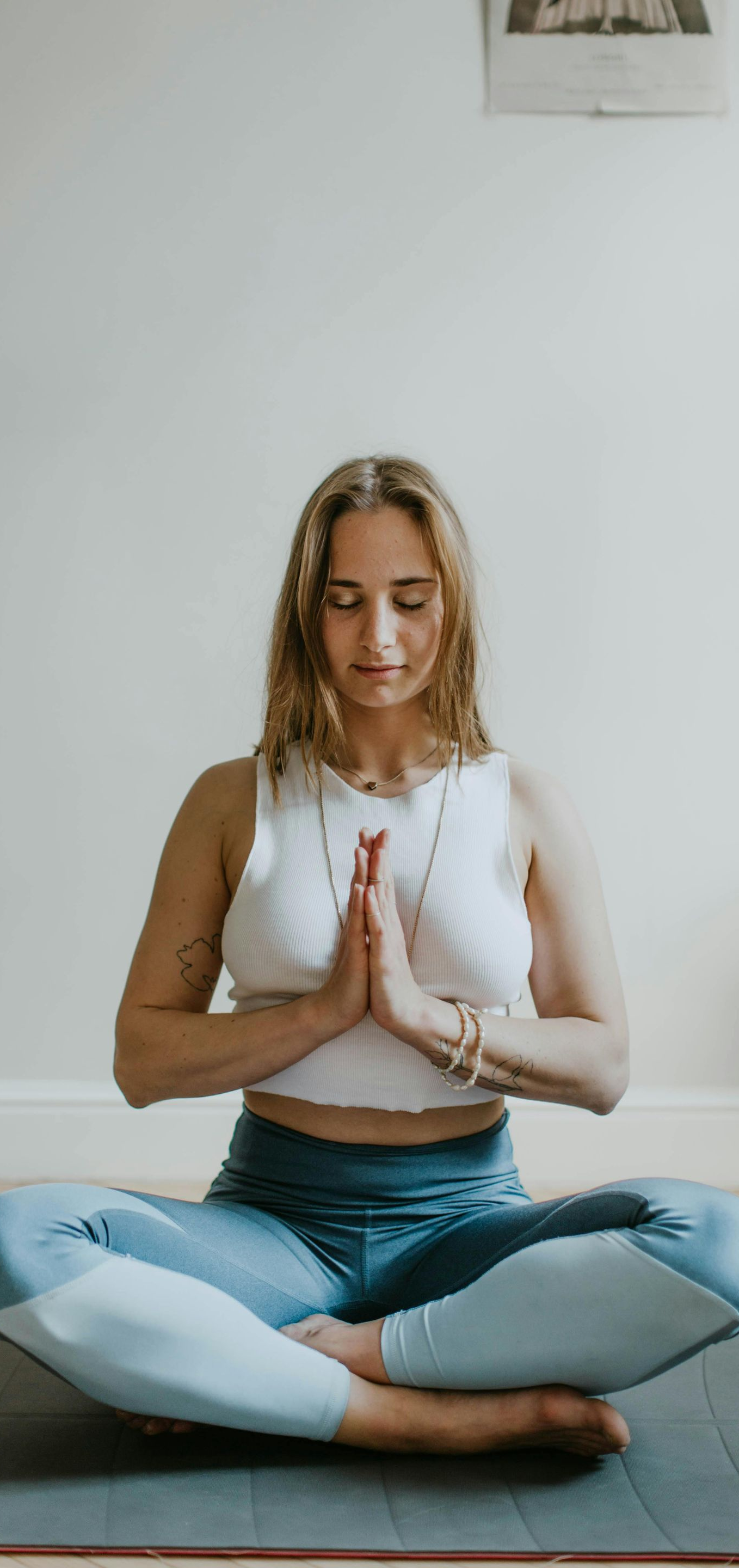 A person in a yoga pose with hands together in prayer position, eyes closed.