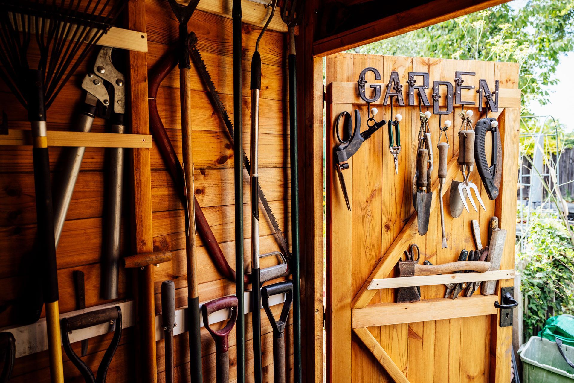 A wooden shed filled with lots of gardening tools.