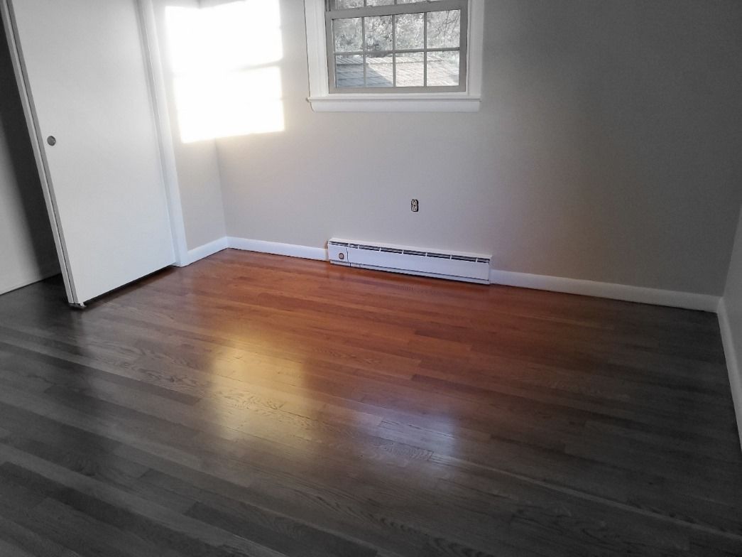 An empty room with hardwood floors and a window
