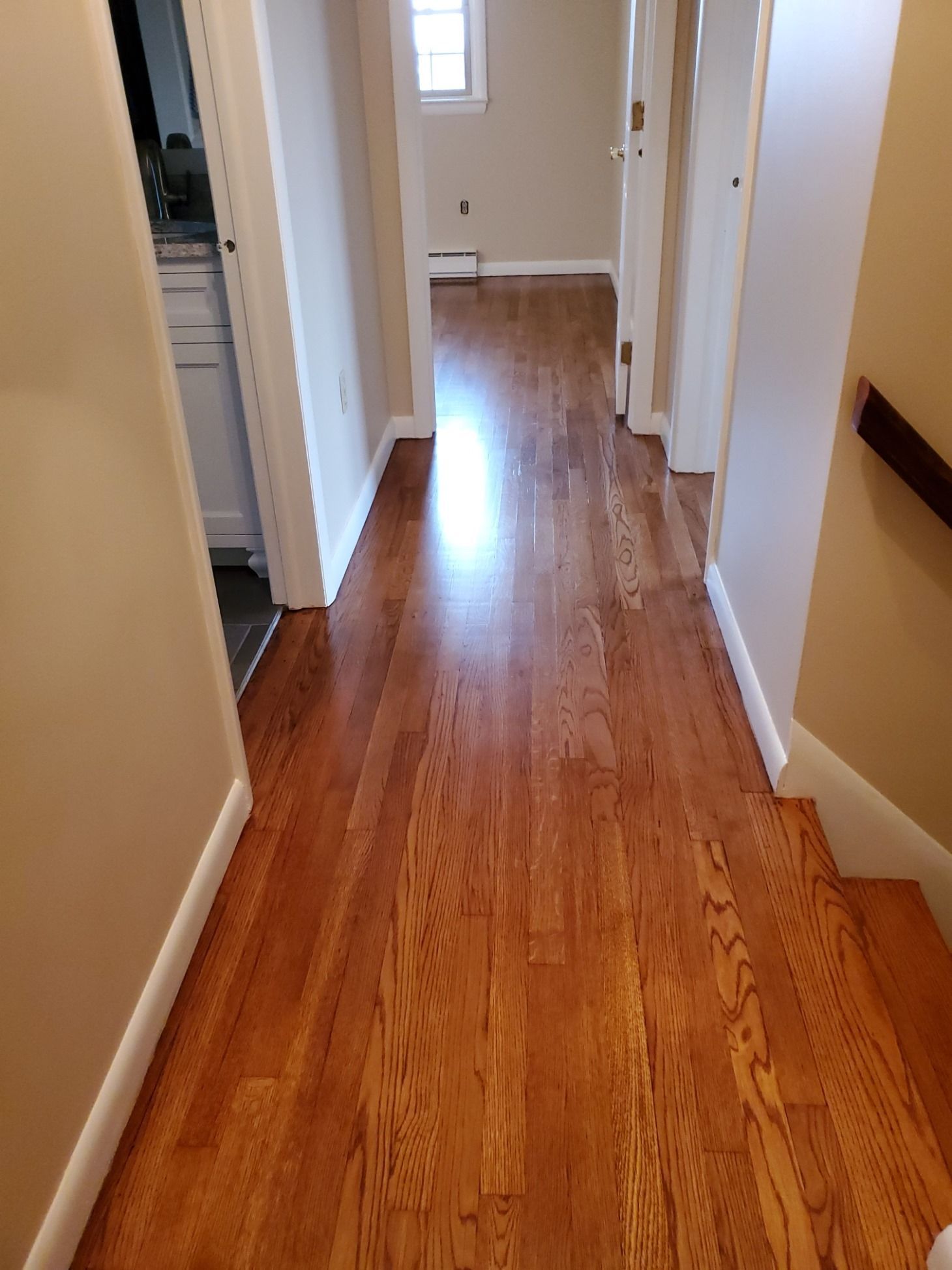 A hallway with hardwood floors and stairs in a house