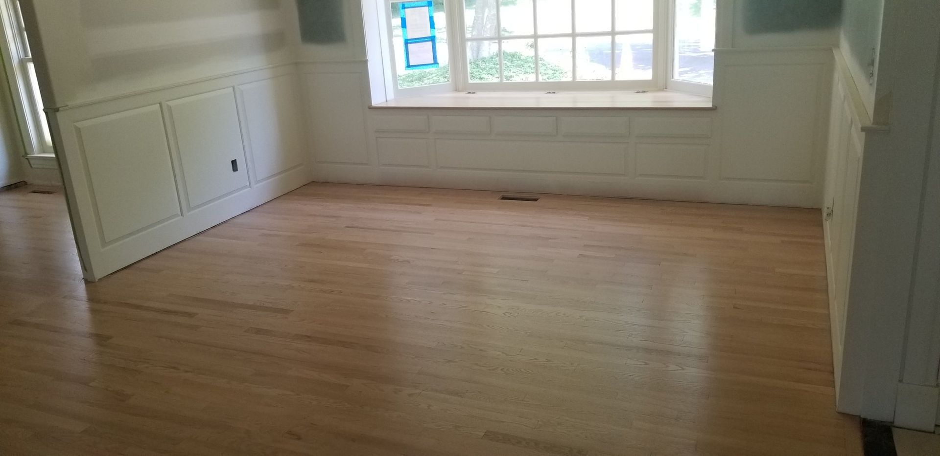 An empty room with wooden floors and a window