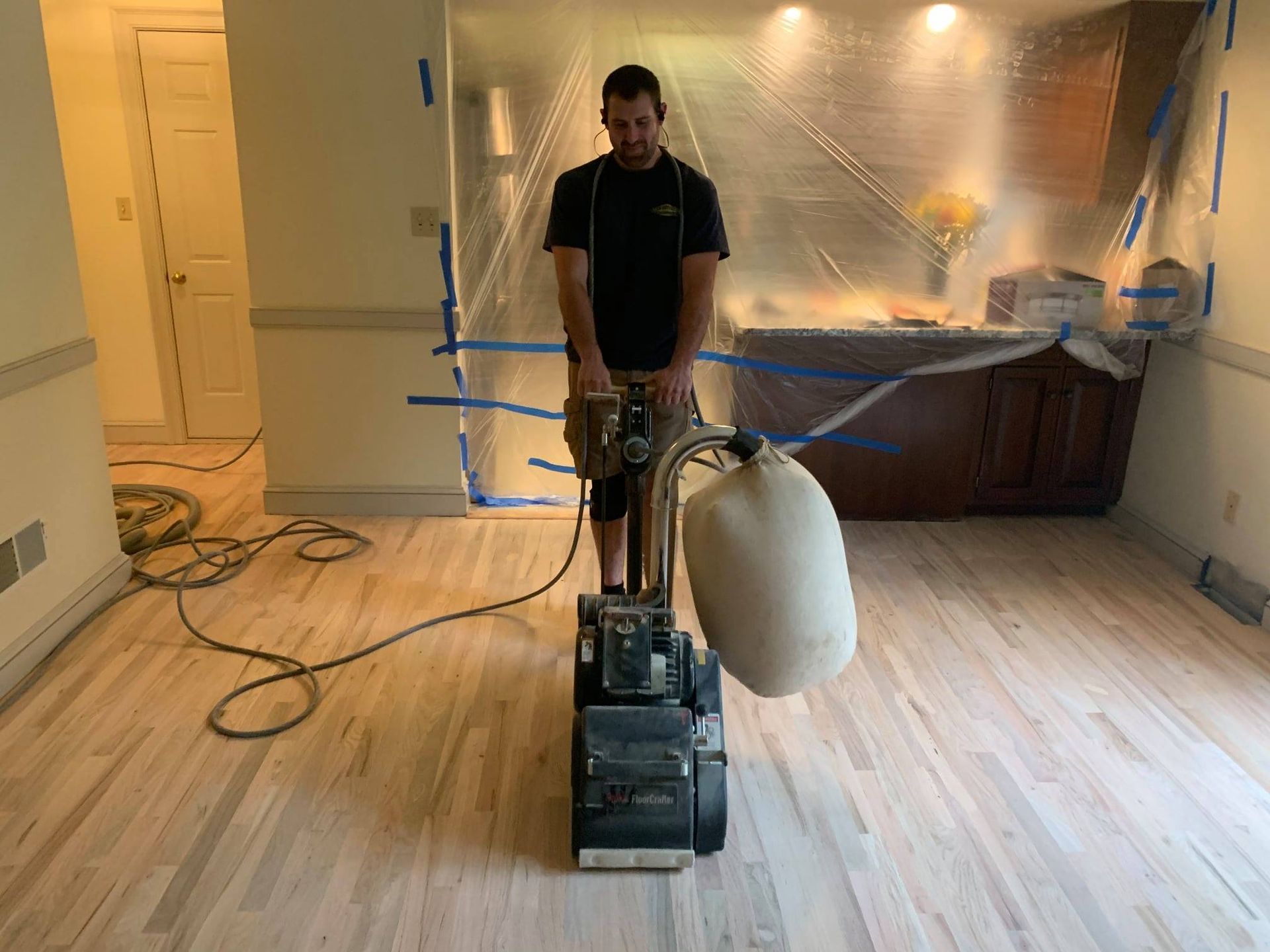 A man is sanding a wooden floor with a machine