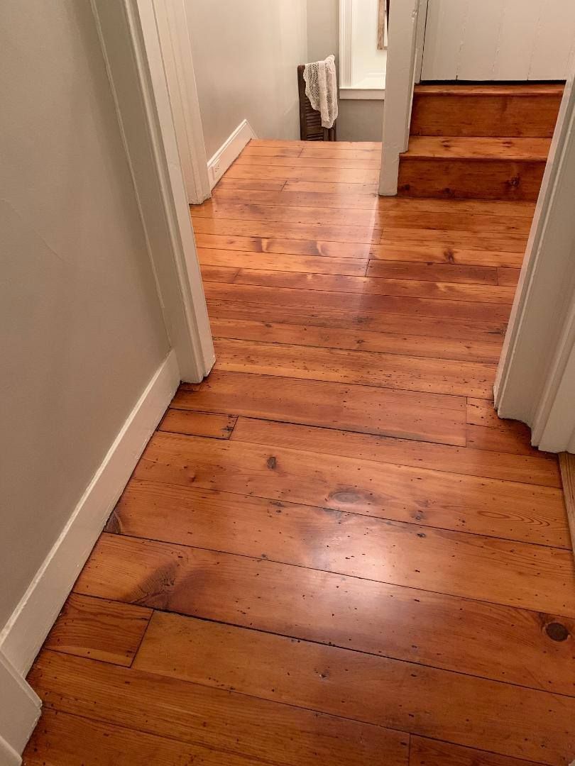 A hallway with a wooden floor and stairs