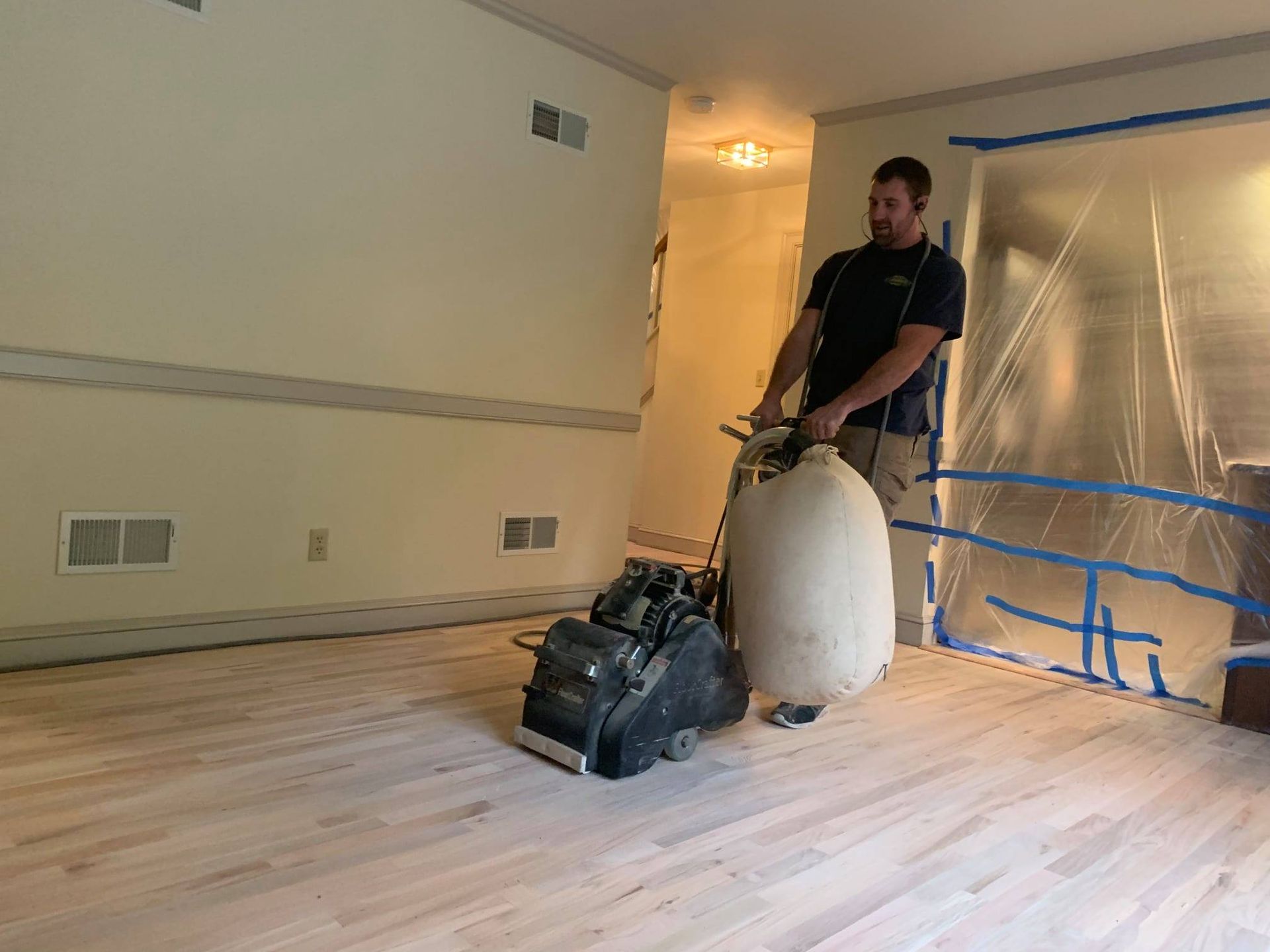 A man is sanding a wooden floor with a machine