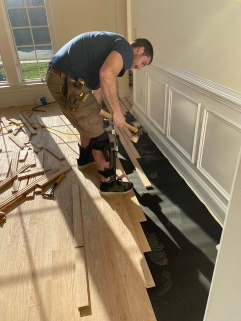 A man is working on a wooden floor in a room