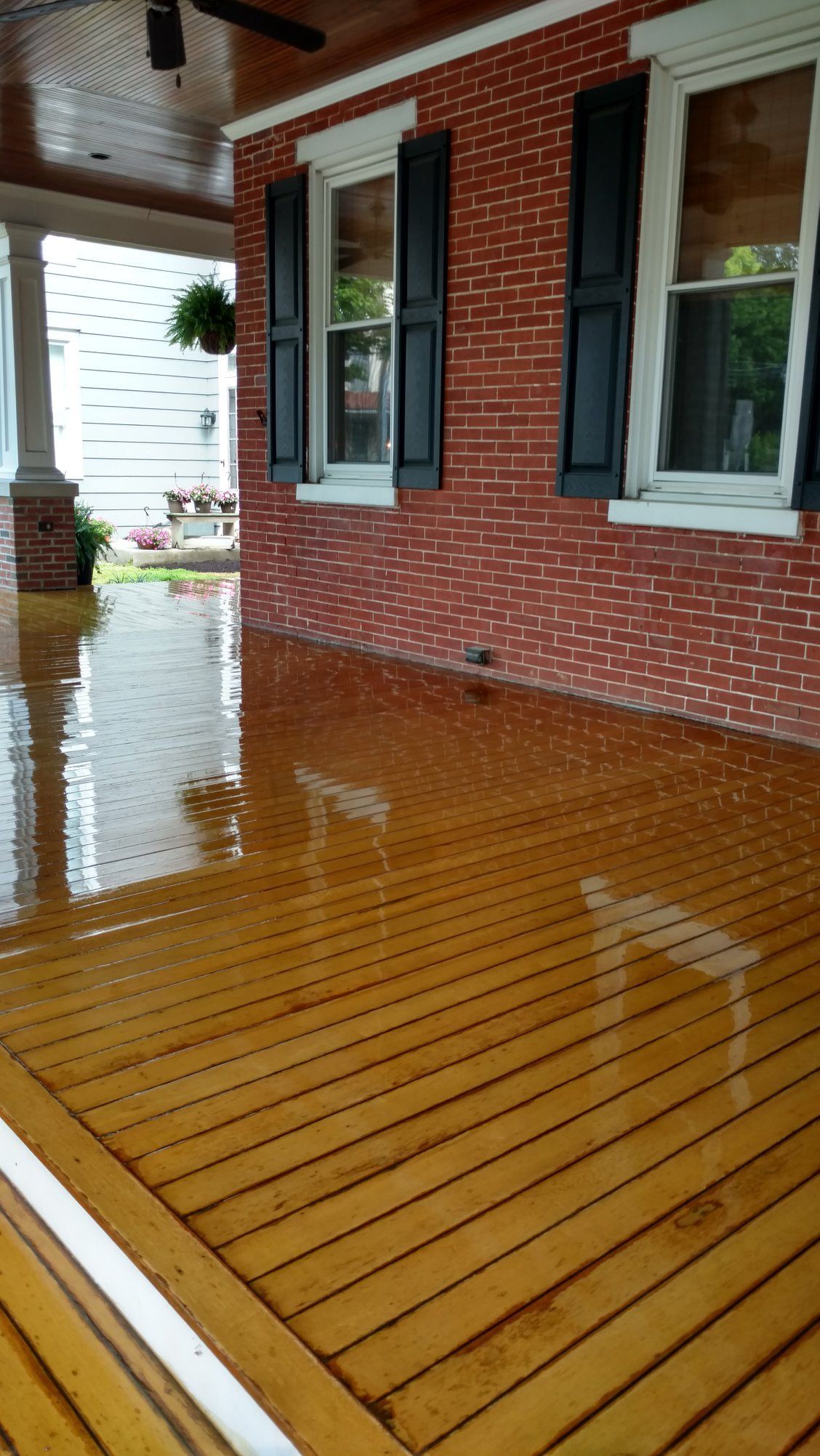 A brick house with black shutters and a wooden deck