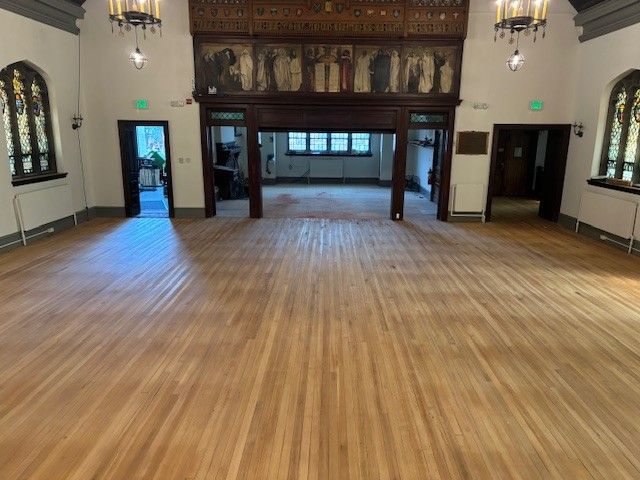 A large room with a wooden floor and a fireplace