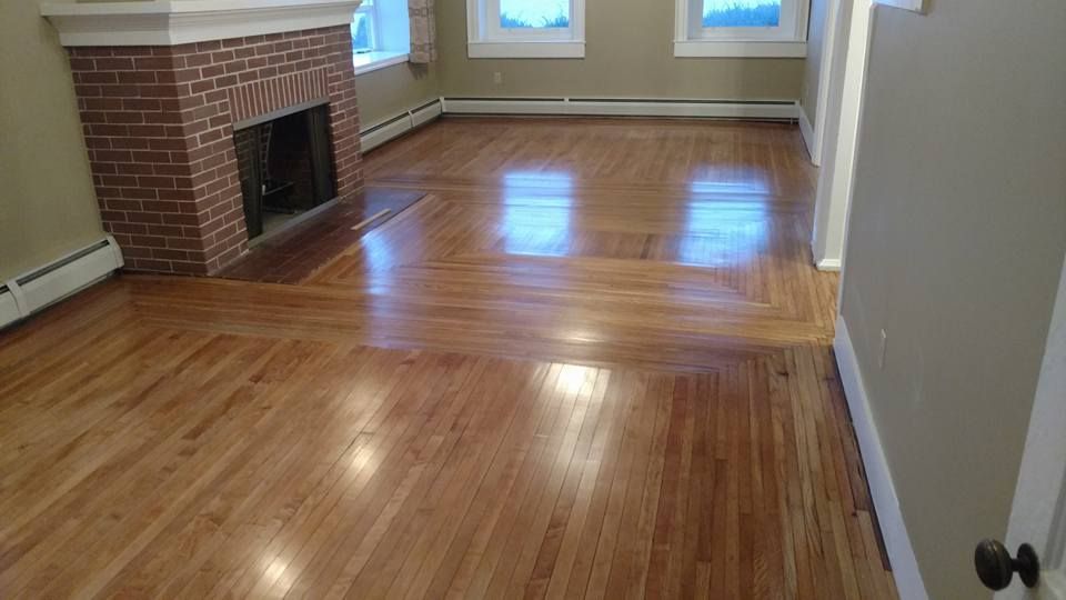 An empty living room with hardwood floors and a fireplace.