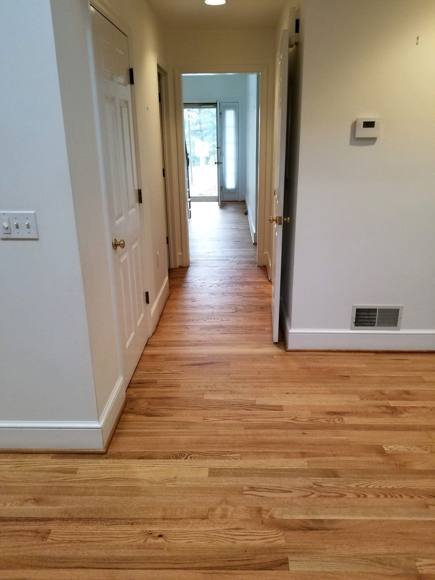 A hallway with hardwood floors and white walls