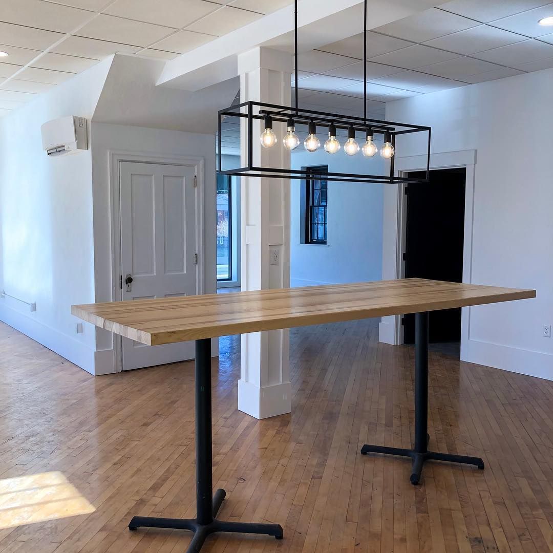 An empty room with a wooden table and lights hanging from the ceiling