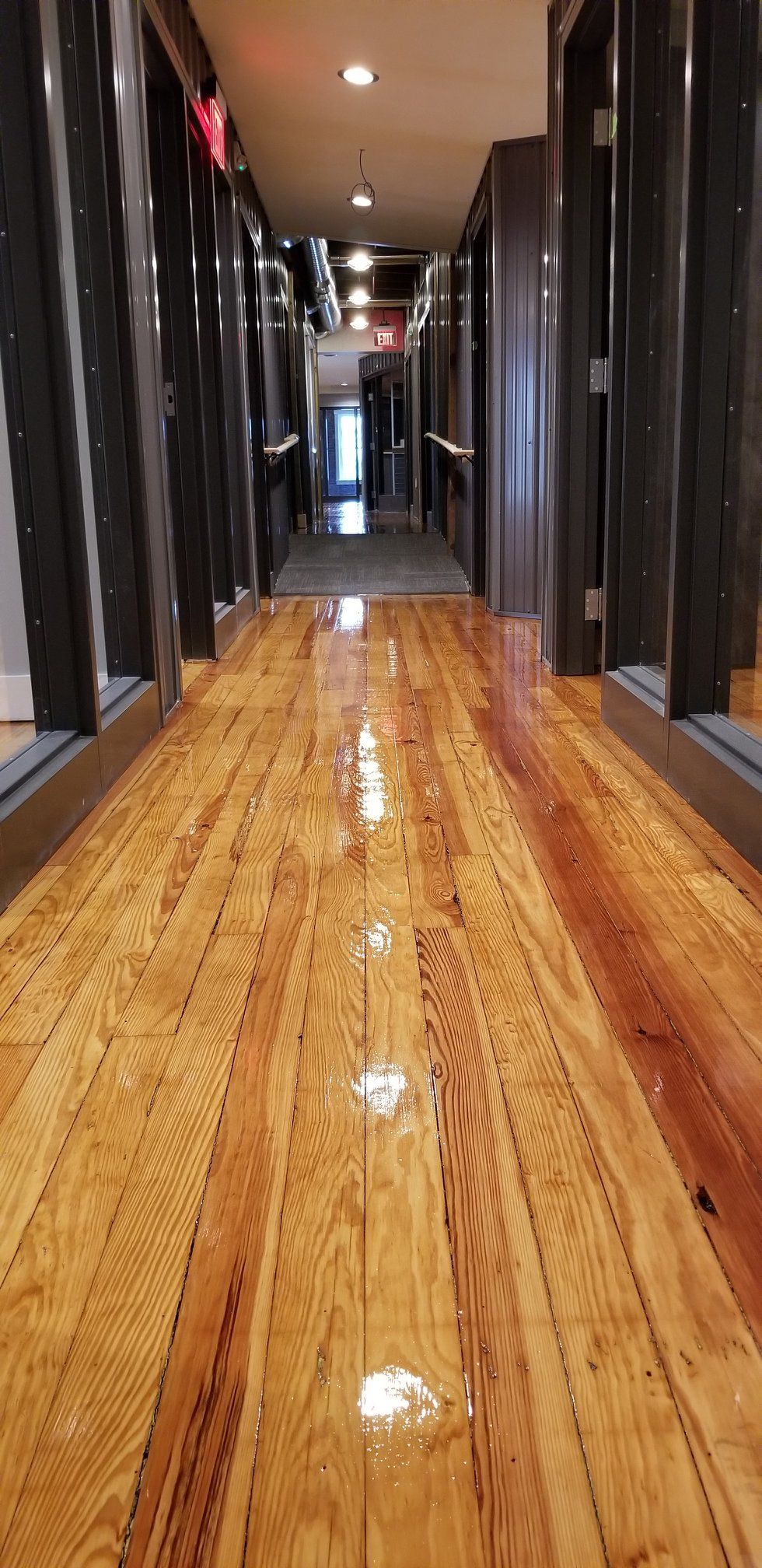 A long hallway with a wooden floor in a building.